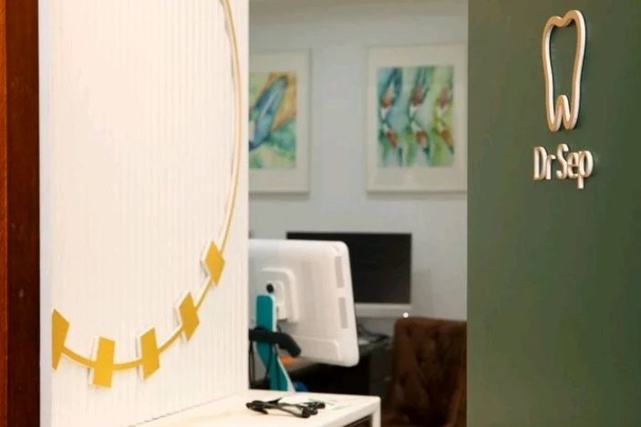 Custom Dr Sep gold logo mounted on a forest green consult room door